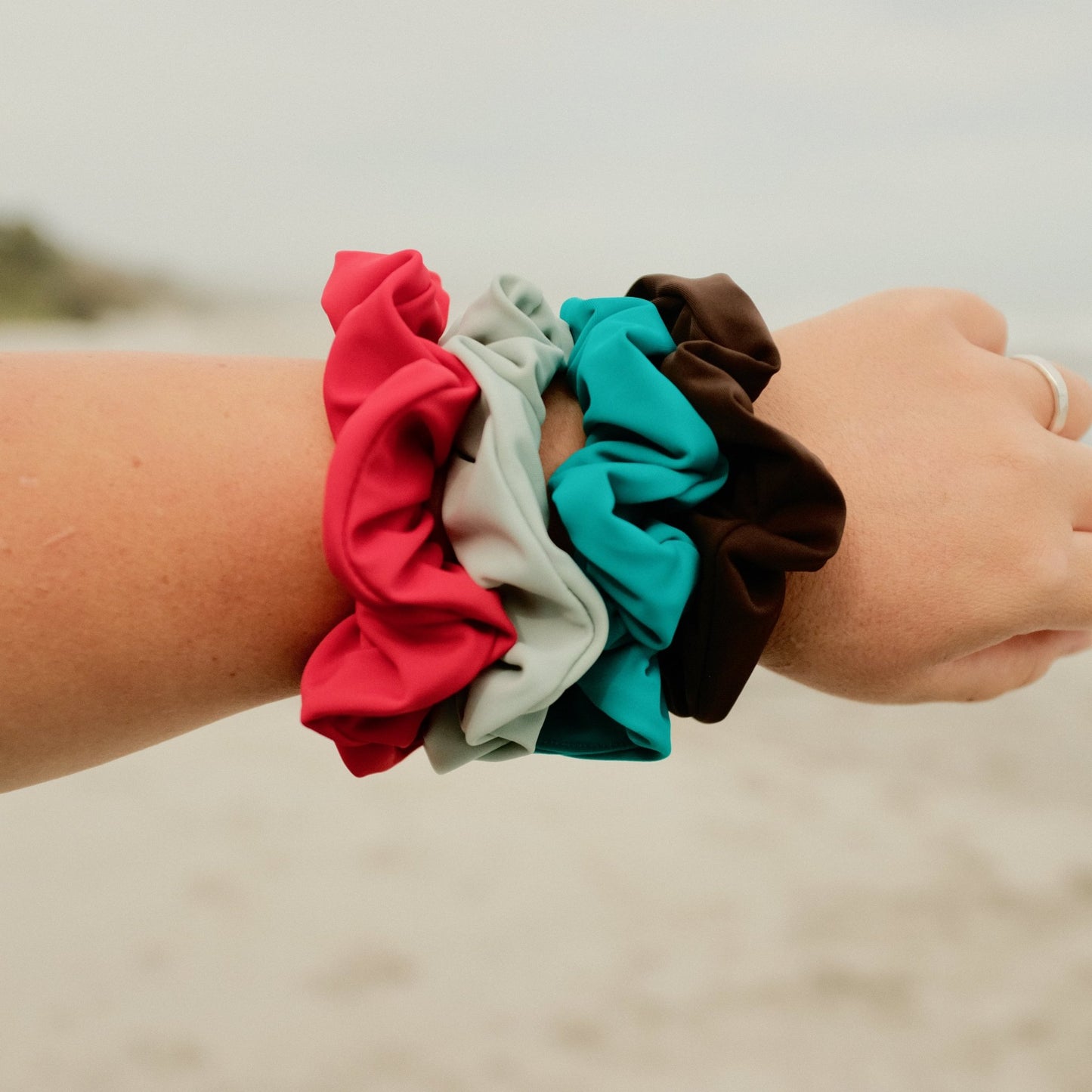 Four scrunchies on women's wrist in Espresso, ocean, mist and siren colours