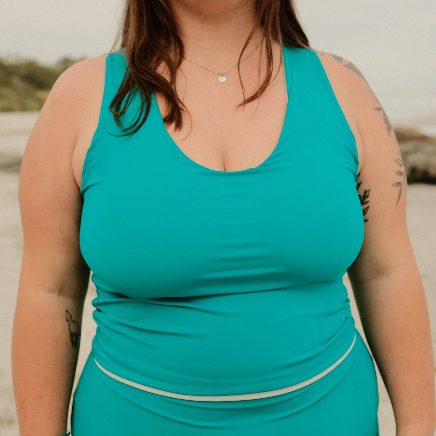 Woman wearing Lola swim top in ocean colour with beach background