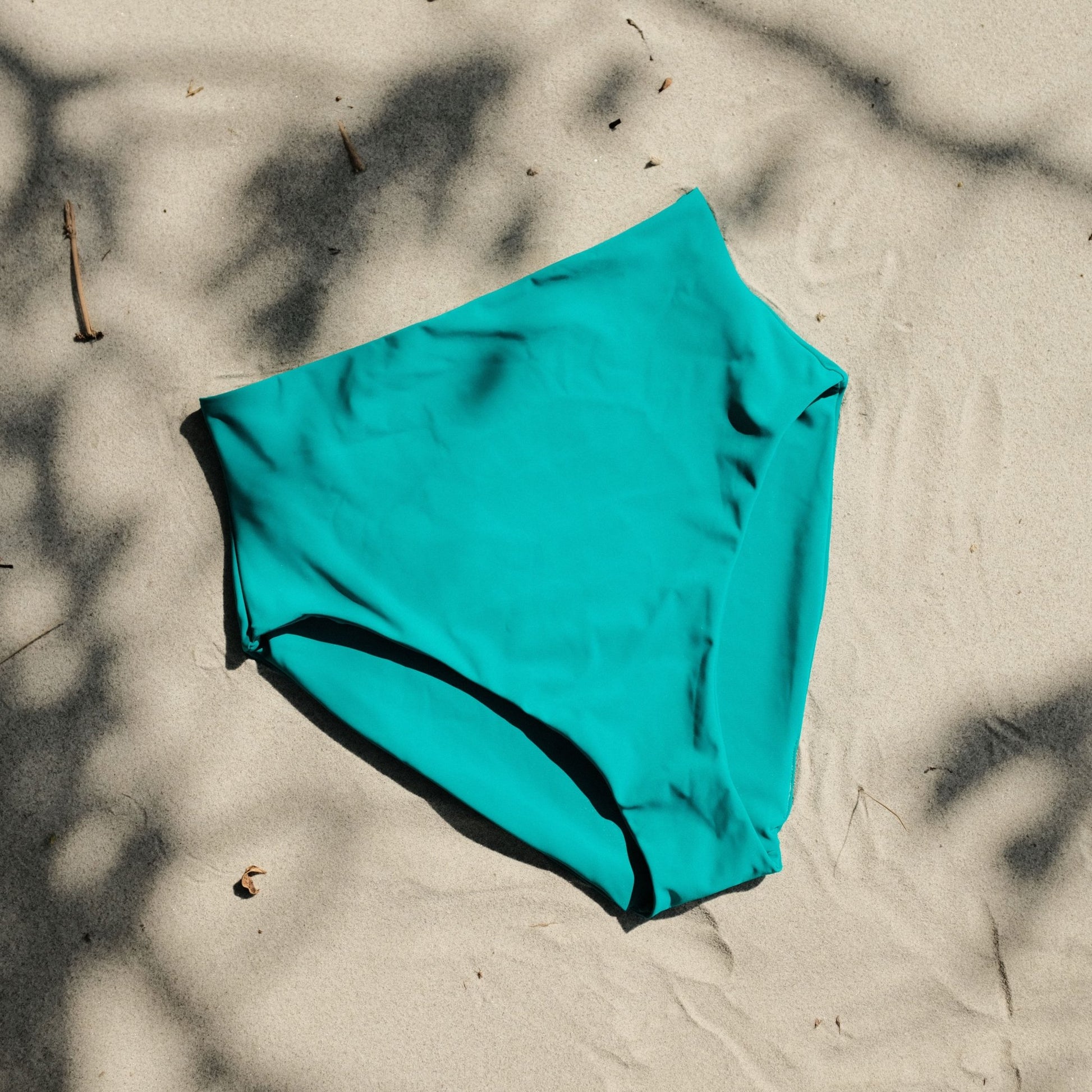 Peach swim bottoms in Ocean colour on sand